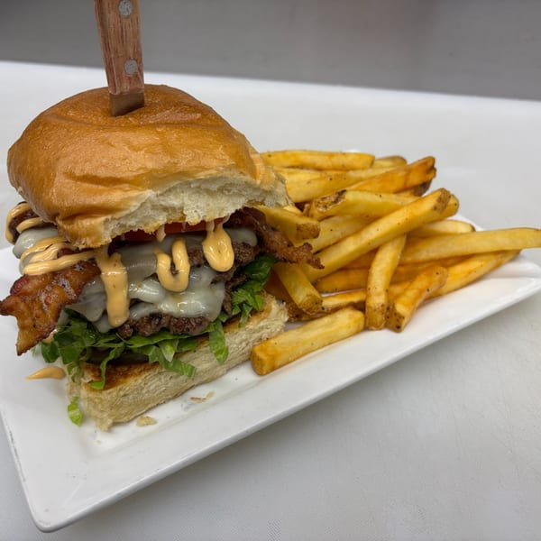 A double cheeseburger with bacon, lettuce, tomato, and special sauce, served with fries.
