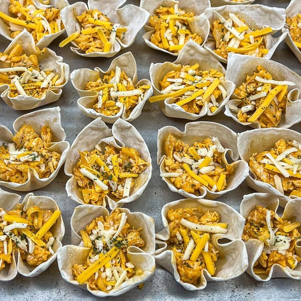 Rows of Pizzeria 131's mini pizza cups, filled with cheese and herbs, ready for baking.